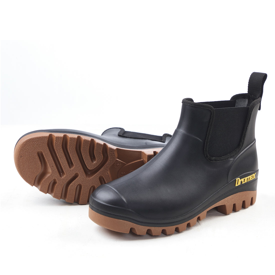 Pair of black rubber boots with brown soles on a white background